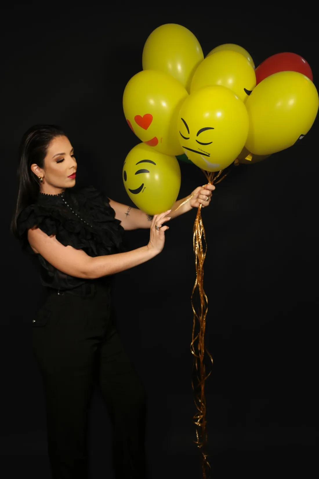 Jéssica Andrapa segurando balões amarelos com rostos de emoji
